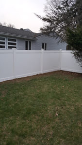 Solid white fence in the corner of a backyard