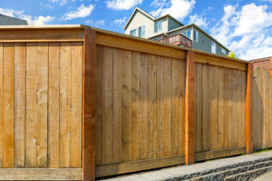 Solid wooden fence with top of home visible in the background