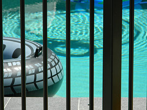 Close up of pool with floaties seen through the bars of an attractive aluminum pool fence