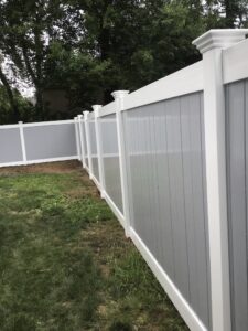 Closeup of impeccable tall white and gray vinyl fence in backyard